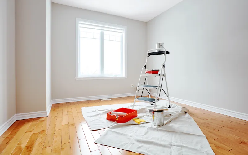 Experienced painter applying even exterior coating along detailed trim and siding