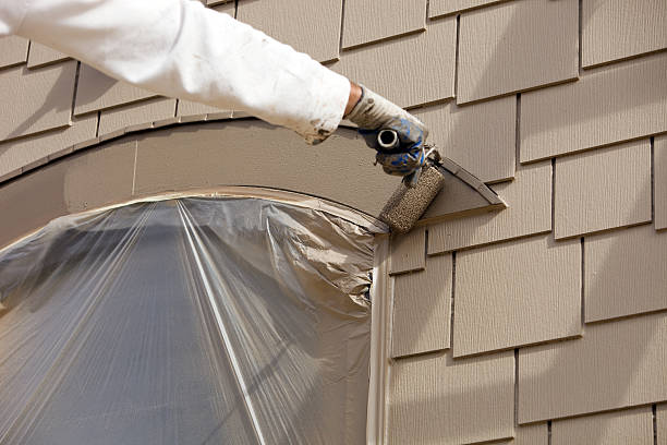 Painter performing exterior painting on wood siding in McAdenville, NC with careful ladder positioning
