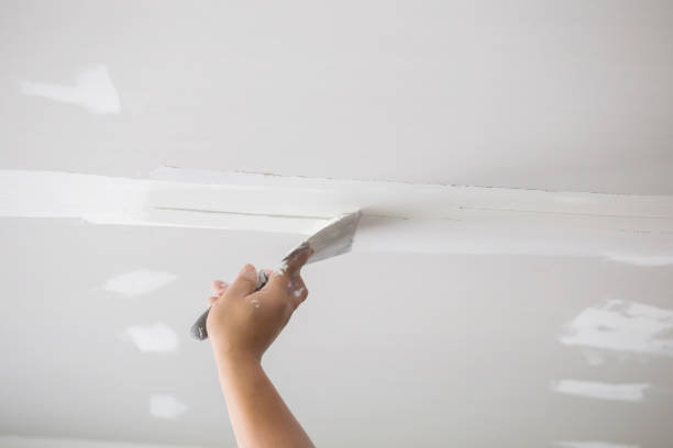 Technician performing drywall repairs inside a Waxhaw, NC home while smoothing a wall patch
